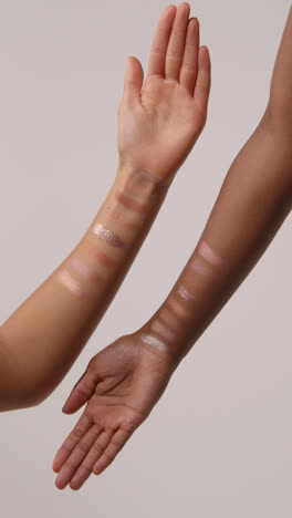 Close-Up-Of-Two-Women's-Arms-With-Colorful-Swatches-Of-Different-Make-Up-Products